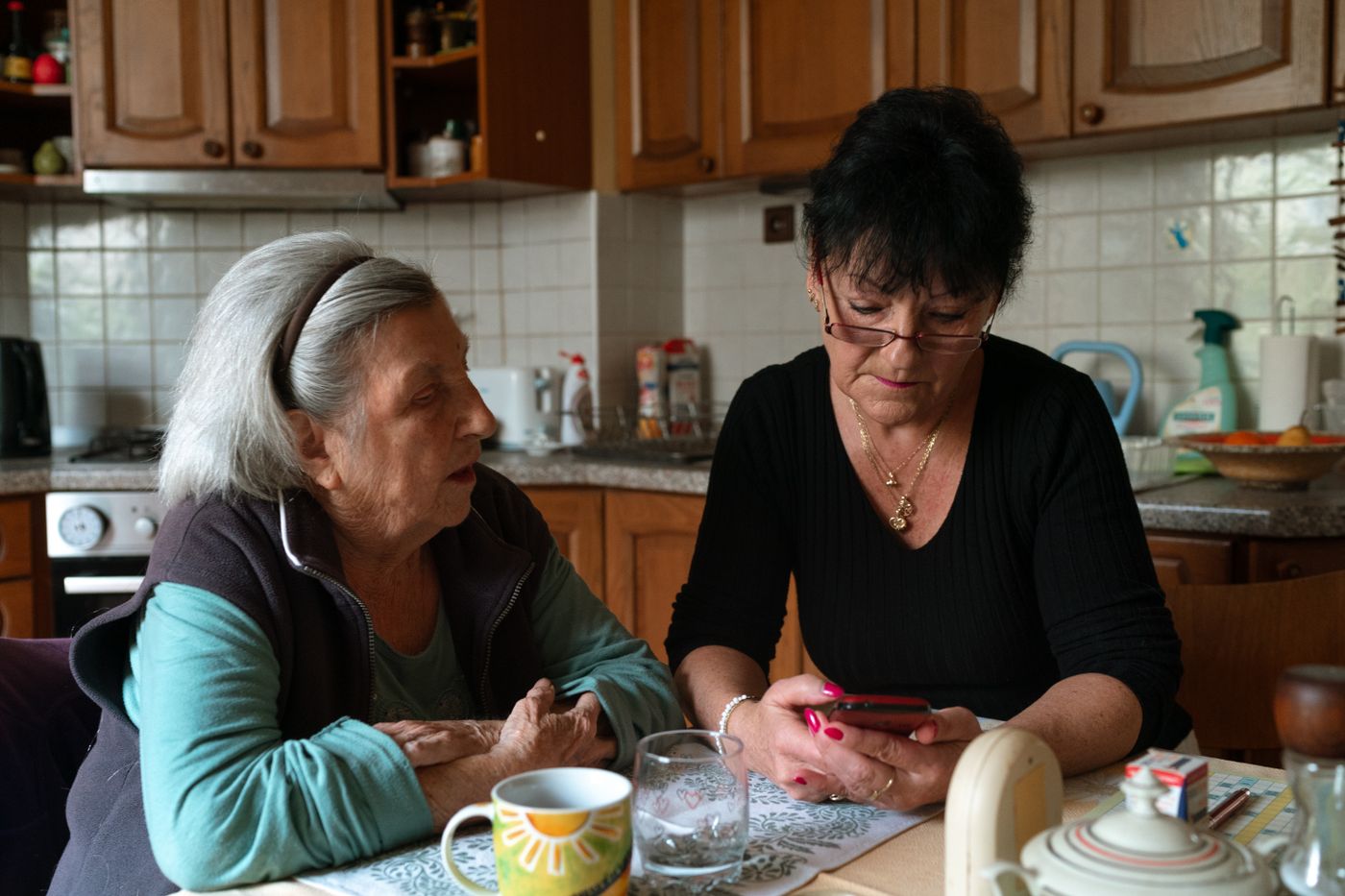 A caregiver and an older woman talking in a home kitchen