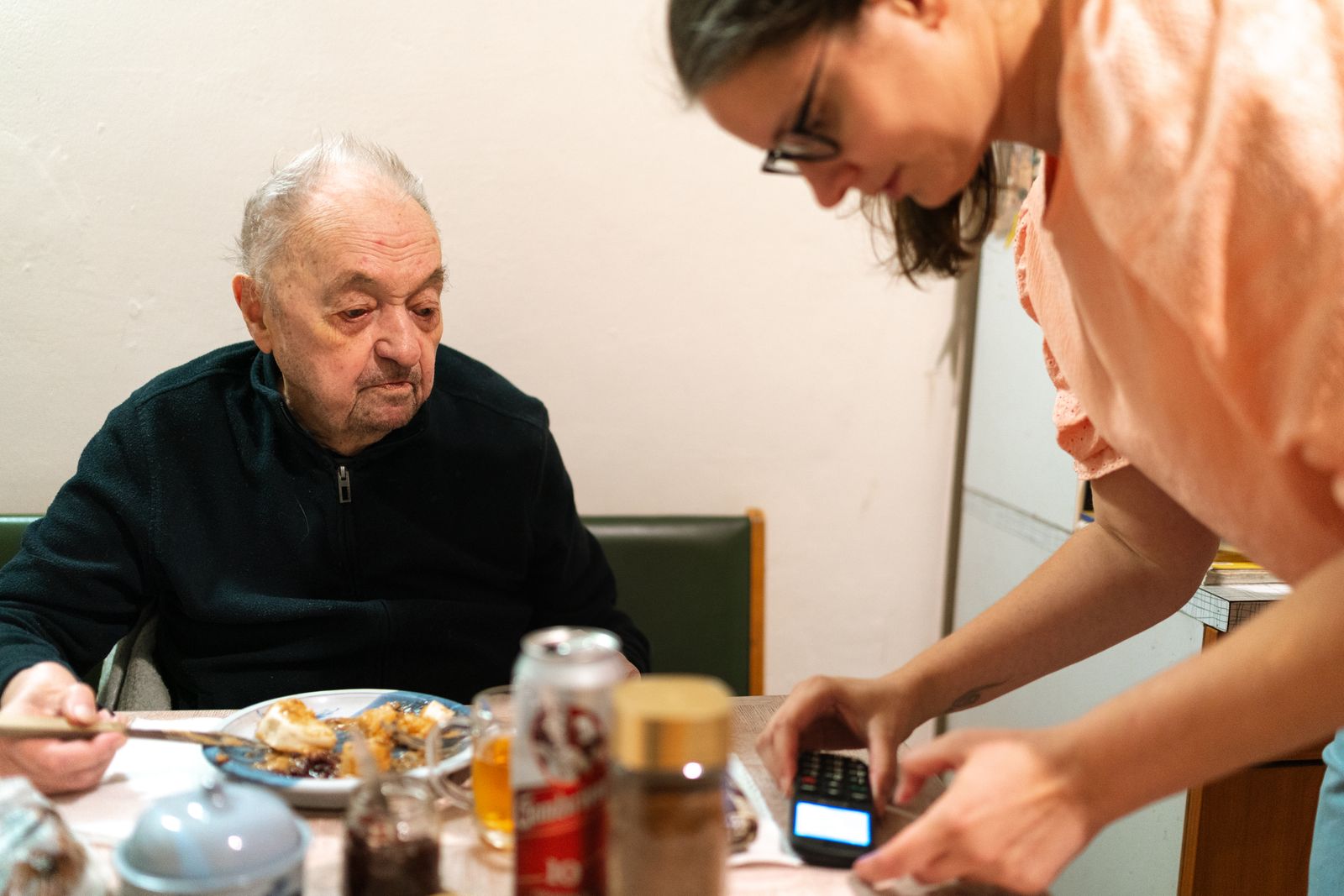 A caregiver assisting an older man during a meal at home